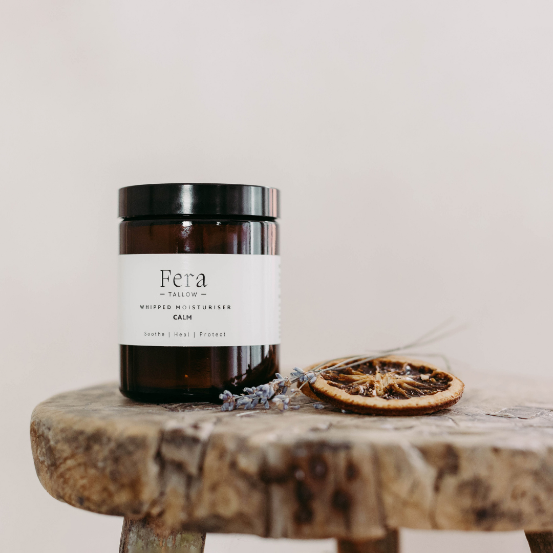 Fera Tallow skincare product on a wooden surface with dried orange and lavender