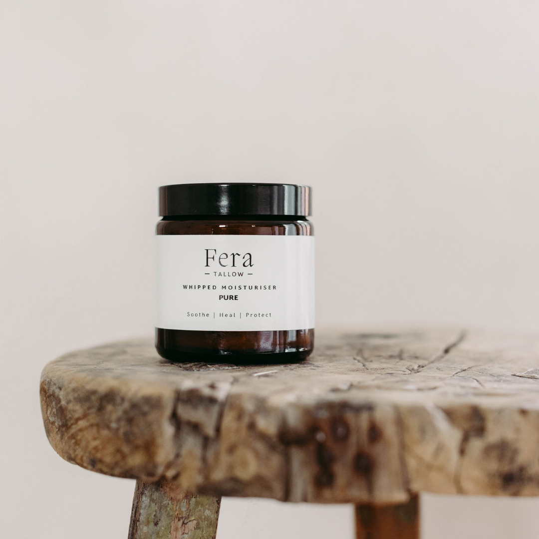 Jar of Fera Tallow Whipped Moisturiser on a wooden stool with a plain background