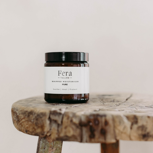 Jar of Fera Tallow Whipped Moisturiser on a wooden stool with a plain background