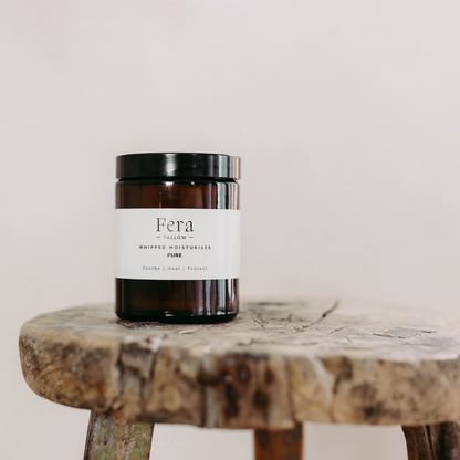 Fera Tallow skincare product jar on a wooden surface with a neutral background
